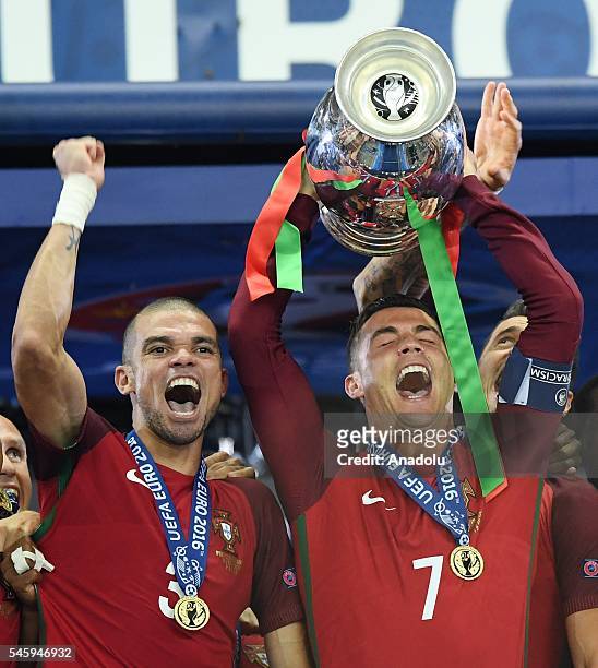 Portugal's forward Cristiano Ronaldo hold up the winners' trophy as he celebrates with teammate Portugal's defender Pepe after beating France 1-0 to...