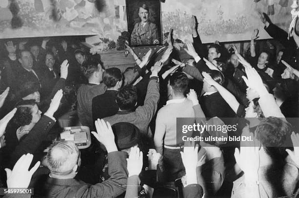 Gäste in einem Lokal in Österreich grüssenein Hitlerbild mit dem 'Deutschen Gruss'.März 1938