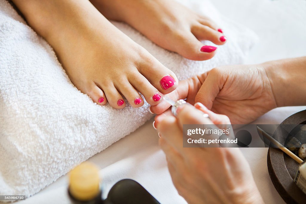 Mujer en salón de uñas recibiendo pedicura por esteticista