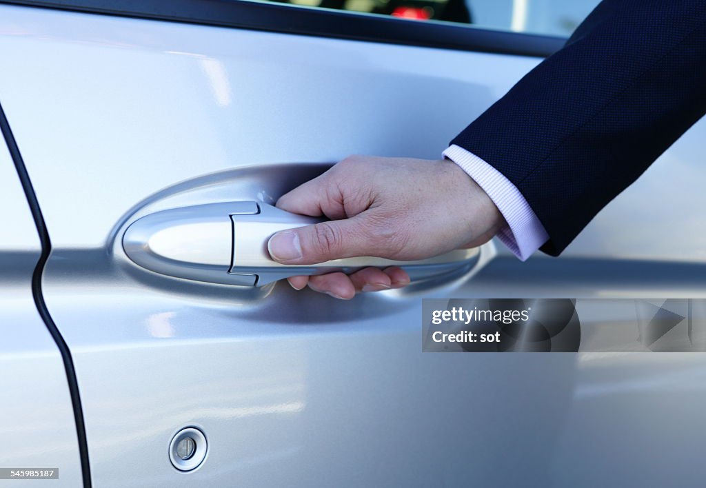 Hand of businessman opening door of car