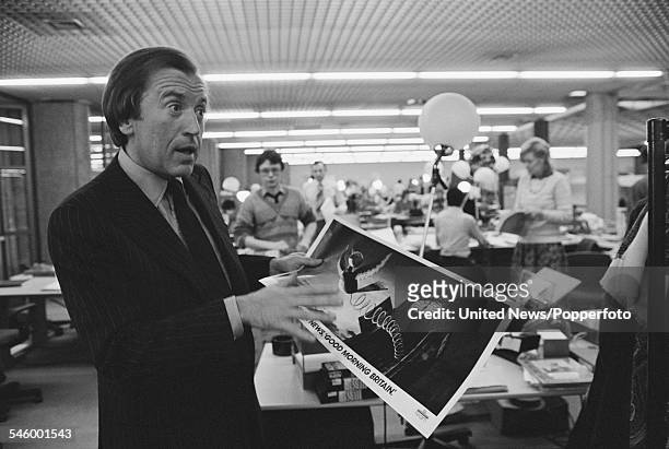 English television and media personality, David Frost pictured holding a promotional poster advertising the launch of TV-am, the ITV franchise for...