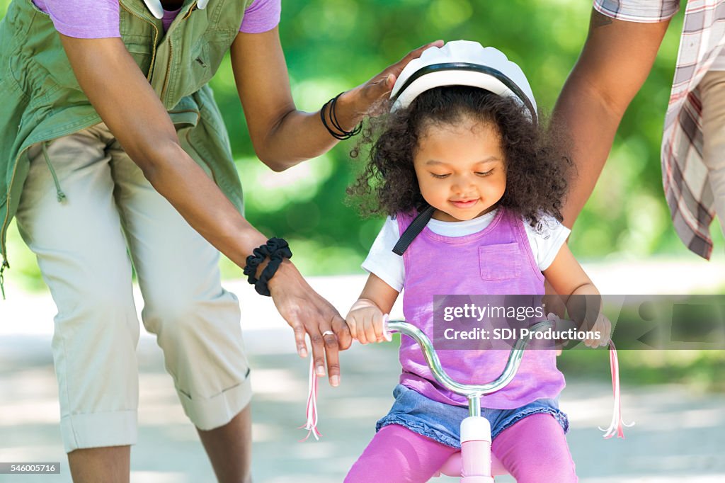 Toddler daughter learning to ride a tricycle