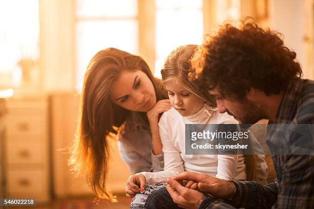 sad little girl at home being consoled by her parents. - tristeza imagens e fotografias de stock