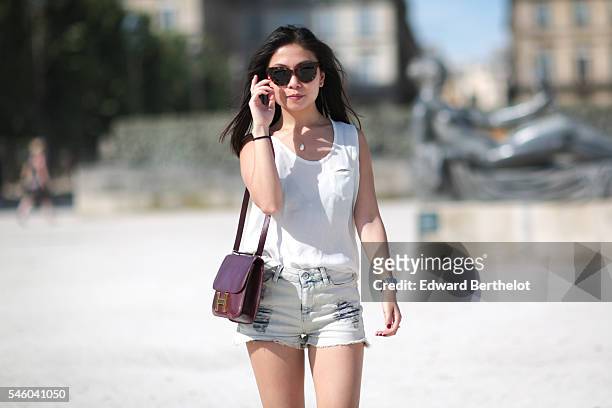May Berthelot , is wearing a The Kooples top, an Iro short, Asos sandals, a Hermes Constance bag, sunglasses, and a necklace from Nine Avril Paris,...