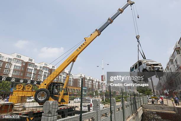 Crane hoists a van out of a river on July 10, 2016 in Xinxiang, China. An overnight rainstorm hit Xinxiang in central China's Henan province and...