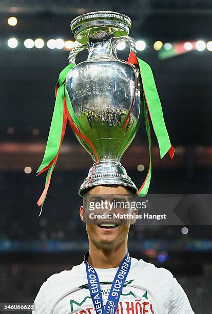 Cristiano Ronaldo of Portugal balances the Henri Delaunay trophy on his head to celebrate after his team's 1-0 win against France in the UEFA EURO...