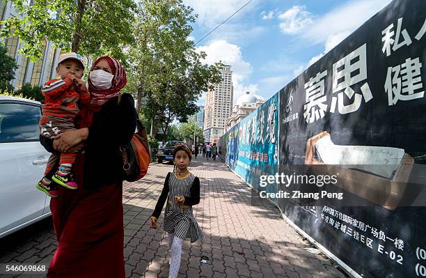 Uygur woman with her children walking on the street. China has taken measures to protect the rights and interests of ethnic minorities, women and...