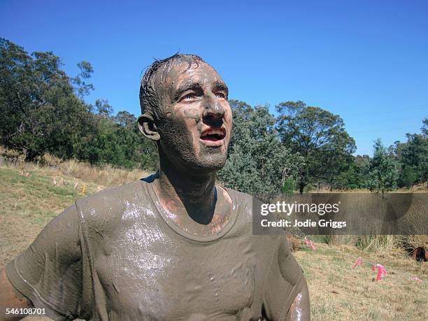 young man covered in mud during obstacle course - mud run stock-fotos und bilder