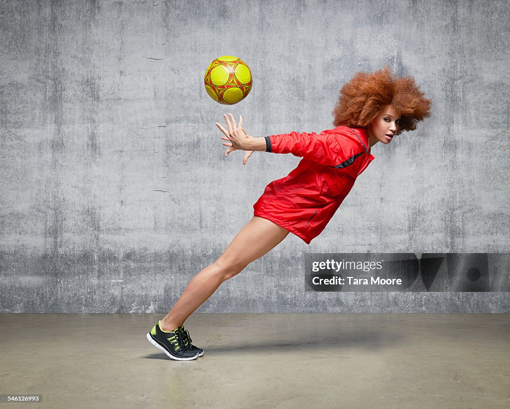 Sportswoman with football suspended in motion