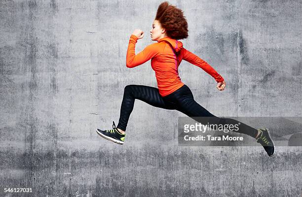 woman jumping in air in urban studio - woman with orange photos et images de collection