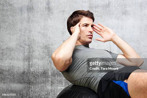 man exercising on gym ball in urban studio setting - sit ups stockfoto's en -beelden