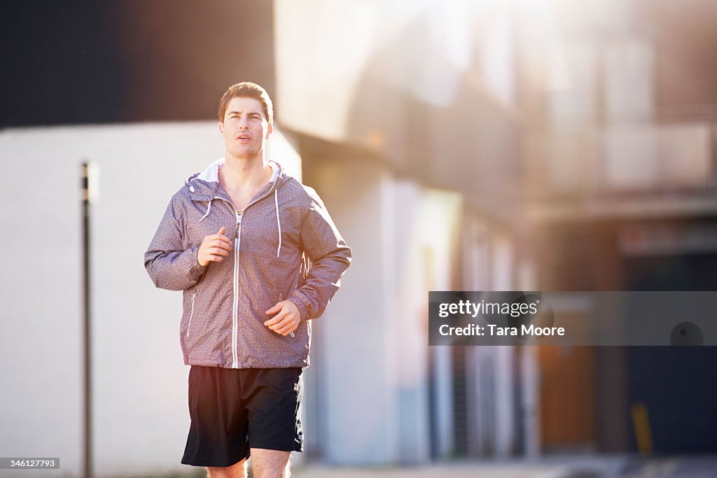 Man running in sunny urban street setting