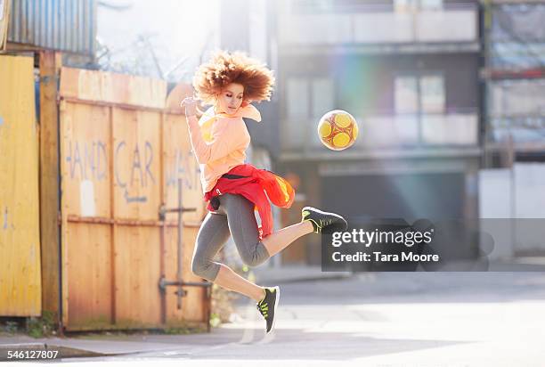 woman exercising with football in urban street - kicking stock-fotos und bilder