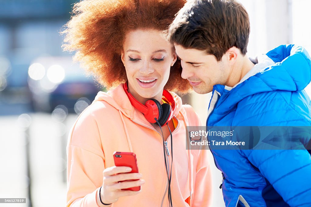 Friends in street with mobile phone and headphones