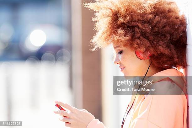 young woman listening to music in the street - coral colored photos et images de collection