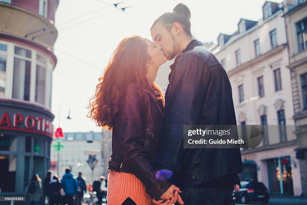 Couple kissing in city.