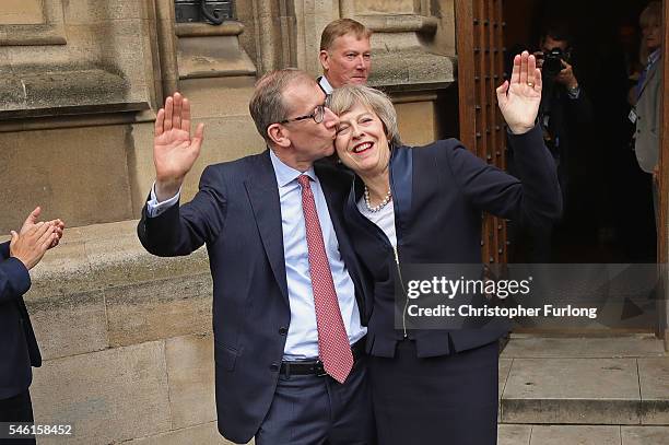 British Home Secretary Theresa May waves with her husband Philip John May as he kisses her head before she makes a statement after Andrea Leadsom...