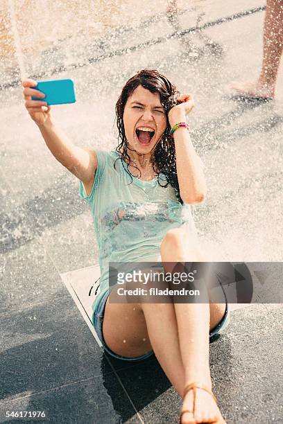 girl taking a selfie under a fountain - doorweekt stockfoto's en -beelden