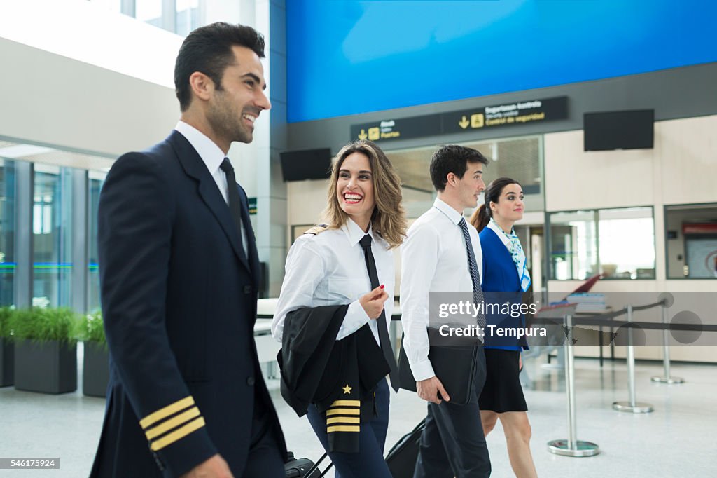 Plane crew walking in airport terminal near airline office.
