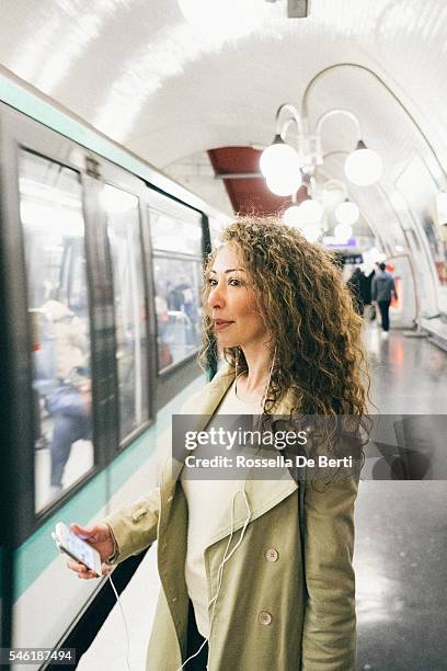 cheerful woman on the phone, subway train on background - paris metro sign stockfoto's en -beelden