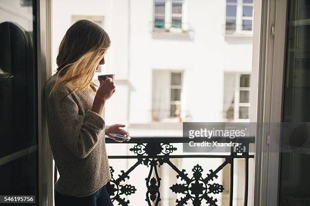 woman drinking coffee at the balcony - paris balcony stock pictures, royalty-free photos & images