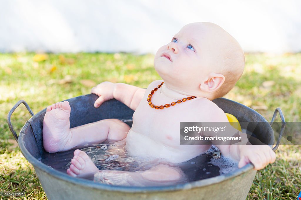 Baby boy sitting in a bucket of water