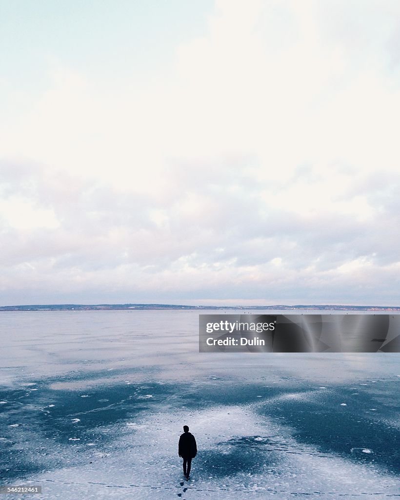 Man walking away across frozen lake