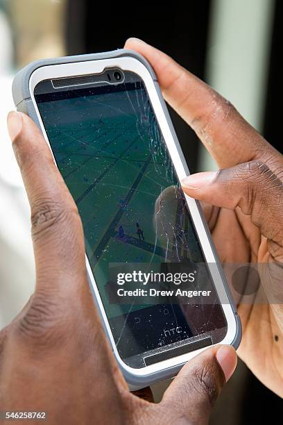 Chris Hamilton plays Pokemon Go on his smartphone outside of Nintendo's flagship store, July 11, 2016 in New York City. The success of Nintendo's new...