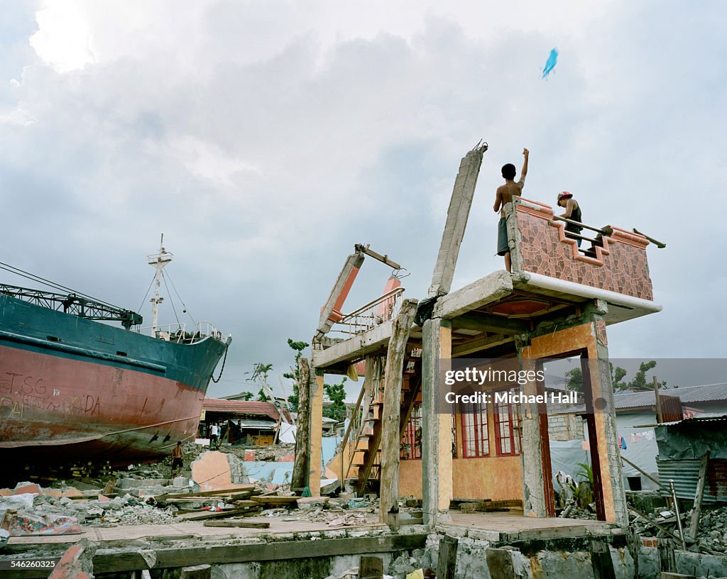 Boys flying kite from remains of ravaged building