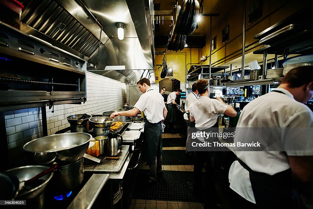 Chef and kitchen staff preparing dinner in kitchen