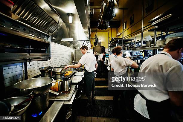 chef and kitchen staff preparing dinner in kitchen - restaurant kitchen stock pictures, royalty-free photos & images