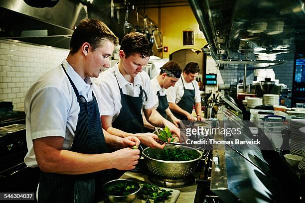 kitchen staff preparing organic greens for dinner - food service occupation stock-fotos und bilder