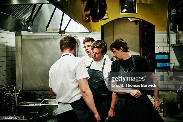chef and kitchen staff discussing food preparation - chef leader - fotografias e filmes do acervo
