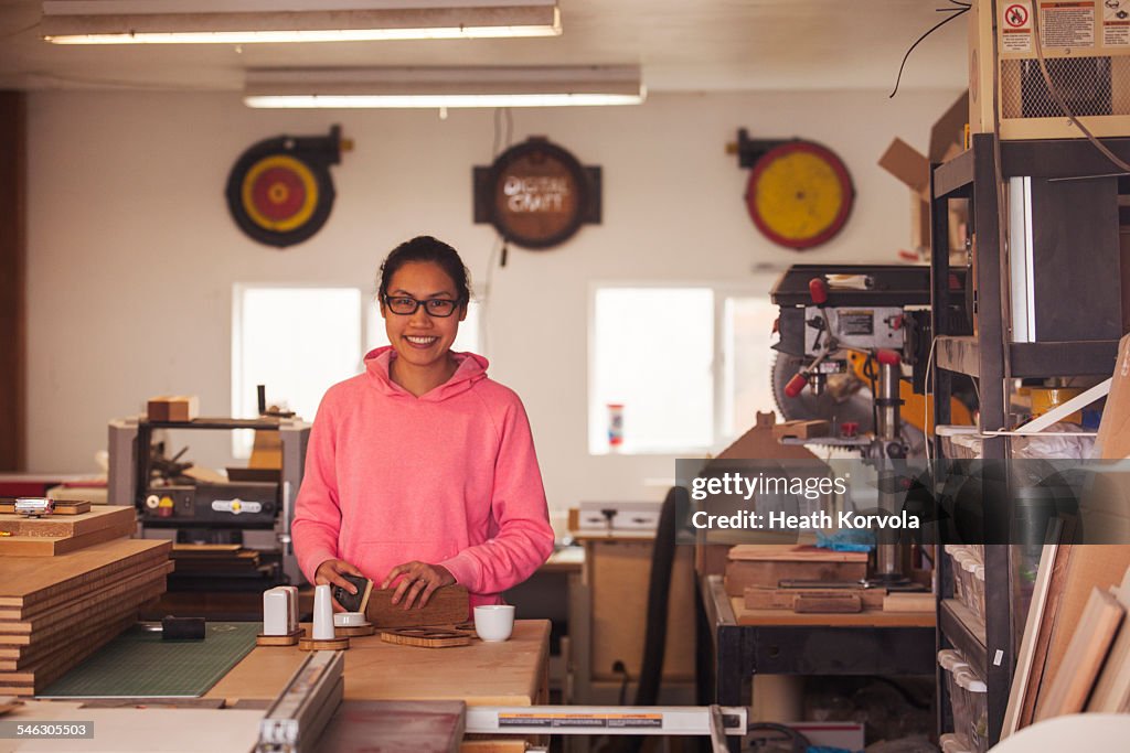 Female maker doing hand work in garage workshop.