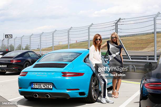 German actress Claudia Eisinger and german actress Julia Dietze on the side of a Porsche 911 Carrera S, both wearing a total look from the Porsche...