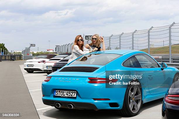 German actress Claudia Eisinger and german actress Julia Dietze on the side of a Porsche 911 Carrera S, both wearing a total look from the Porsche...