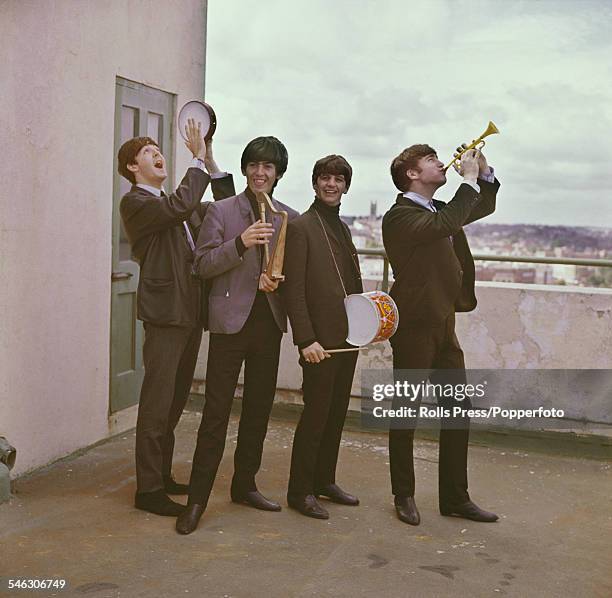 English pop group The Beatles pictured playing children's musical instruments on the roof of a building in London in 1964. From left to right: Paul...