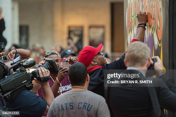 Cool J signs a graffiti board as he arrives for "VH1's Hip Hop Honors: All Hail The Queens" on July 11, 2016 at Lincoln Center in New York. / AFP /...