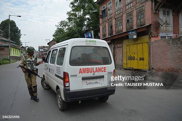 An Indian paramilitary trooper stops an ambulance during a curfew in Srinagar on July 12, 2016. Thirty protesters were killed and over 300 injured in...