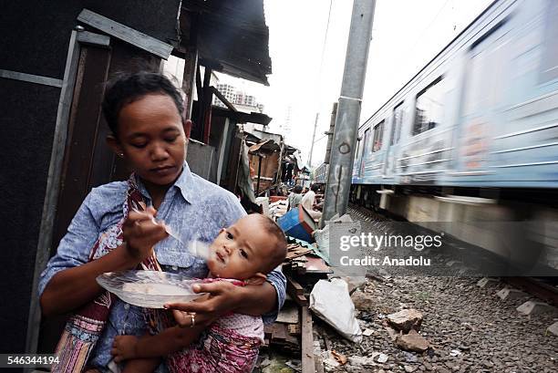 Woman feeds her baby near the railway tracks at the Slum area in Jakarta, Indonesia, on July 11, 2016. Indonesia is the most populous country in...