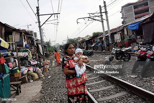 An Indonesian mother with a baby poses on the railway tracks at the slum area in Jakarta, Indonesia, on July 11, 2016. Indonesia is the most populous...