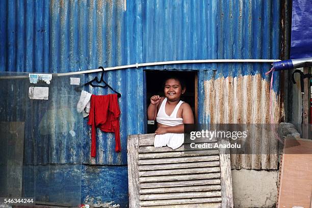 An Indonesian kid looks out from a window of near a makeshift shack near the railway tracks at the slum area in Jakarta, Indonesia, on July 11, 2016....