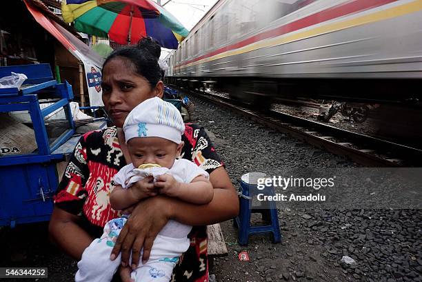 An Indonesian mother with a baby poses on the railway tracks at the slum area in Jakarta, Indonesia, on July 11, 2016. Indonesia is the most populous...