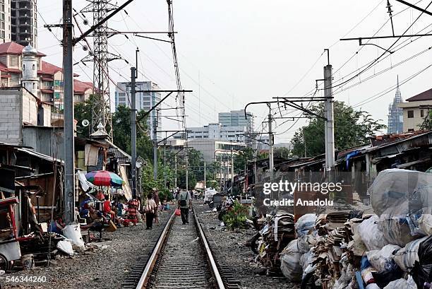 Residents walk pass makeshift shacks near the railway tracks at the slum area in Jakarta, Indonesia, on July 11, 2016. Indonesia is the most populous...