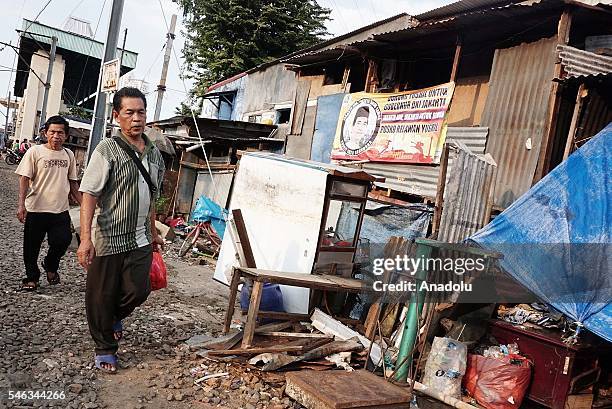 Two men walk pass makeshift shacks near the railway tracks at the slum area in Jakarta, Indonesia, on July 11, 2016. Indonesia is the most populous...