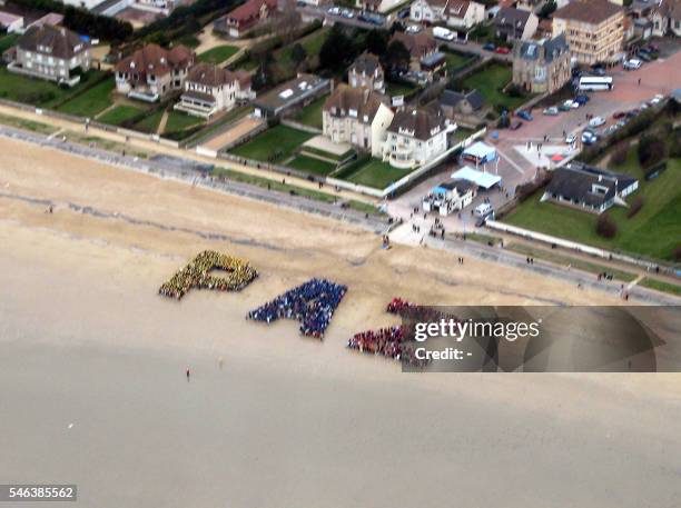 An aerian view shows people participating in a gathering to write "Paz" in human letters on a Normandy beach landing in Hermanville-Sur-Mer, 04 March...