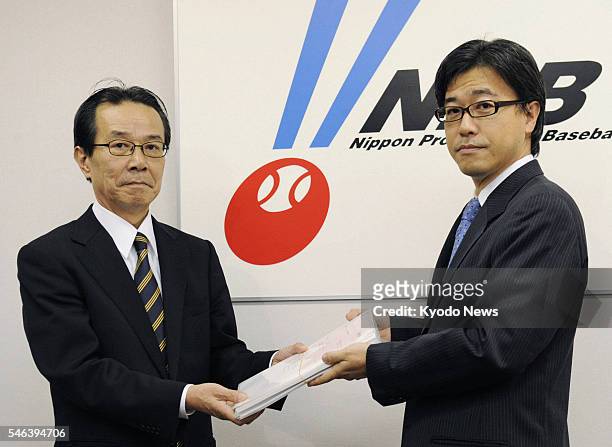 Japan - Makoto Haruta , director and chairman of DeNA Co., hands an application to Kunio Shimoda, secretary general of Nippon Professional Baseball,...