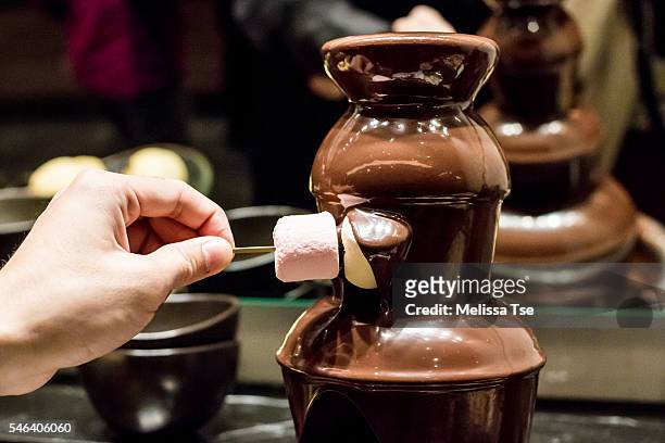 dipping marshmallow in chocolate fountain - chokladfondue bildbanksfoton och bilder