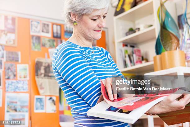 glass designer looking through art book in studio. - catalogo stock-fotos und bilder