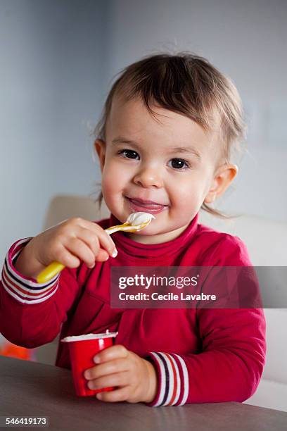 toddler girl eating yogurt - baby eating yogurt stockfoto's en -beelden